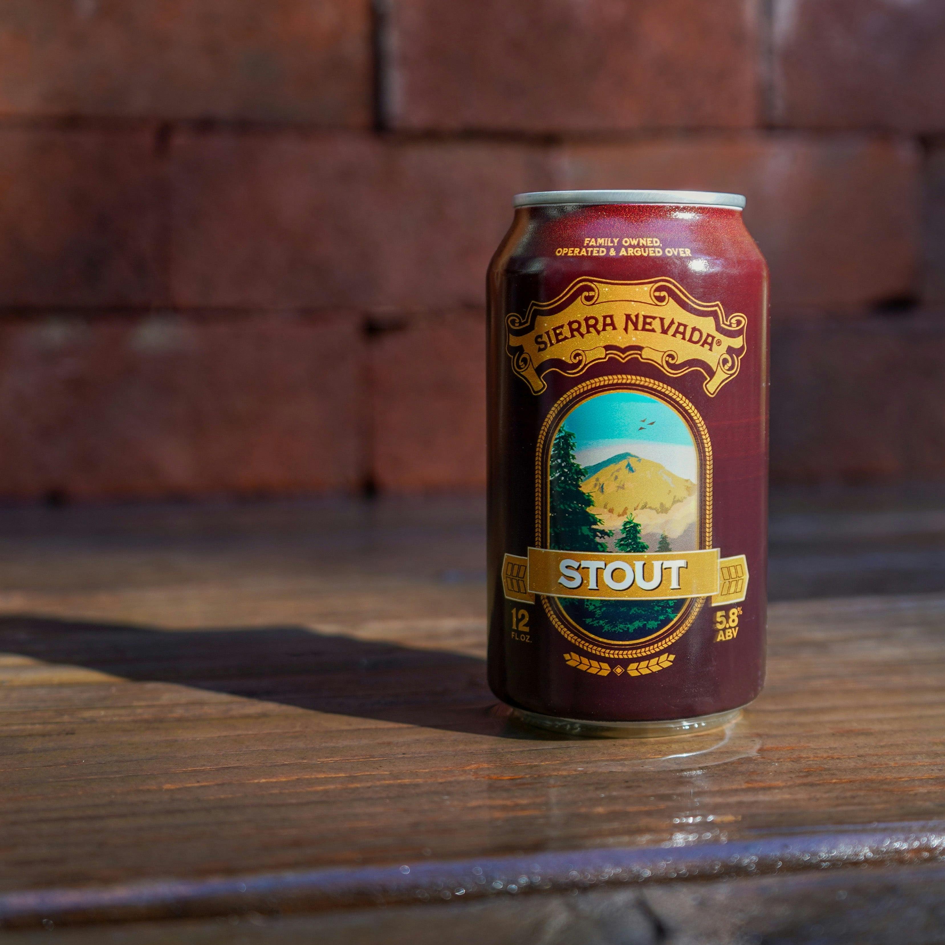 A 12oz can of Sierra Nevada Stout sits on a wooden bar in front of a brick wall