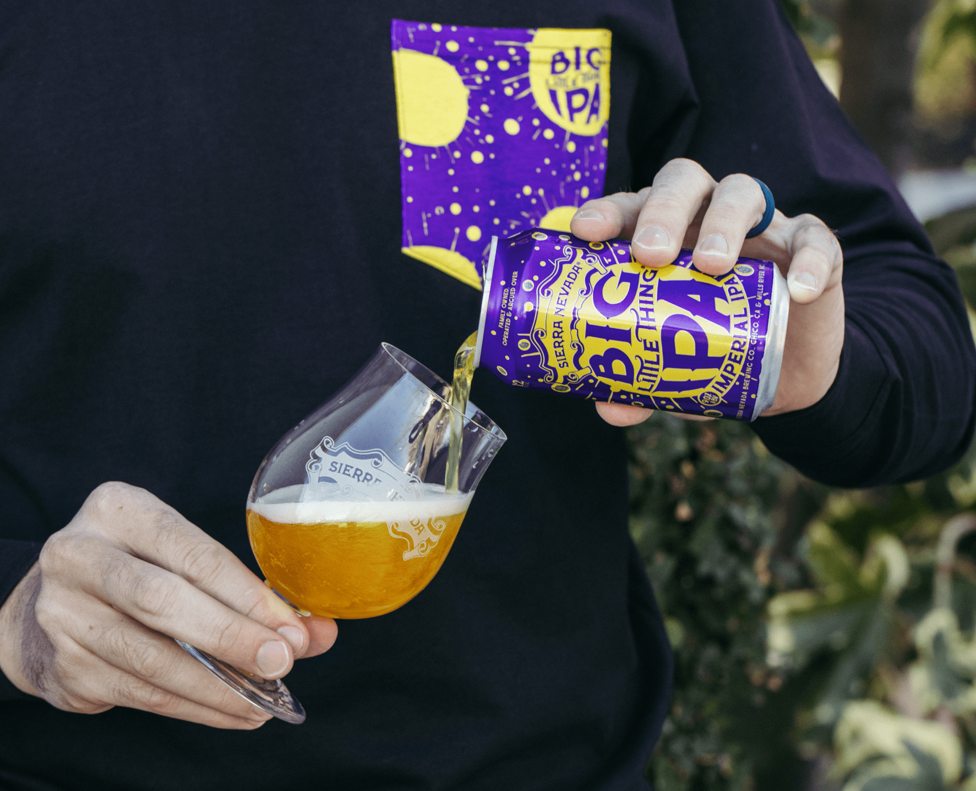 Man wearing a Big Little Thing shirt while pouring a can of Big Little Thing beer into a Sierra Nevada glass